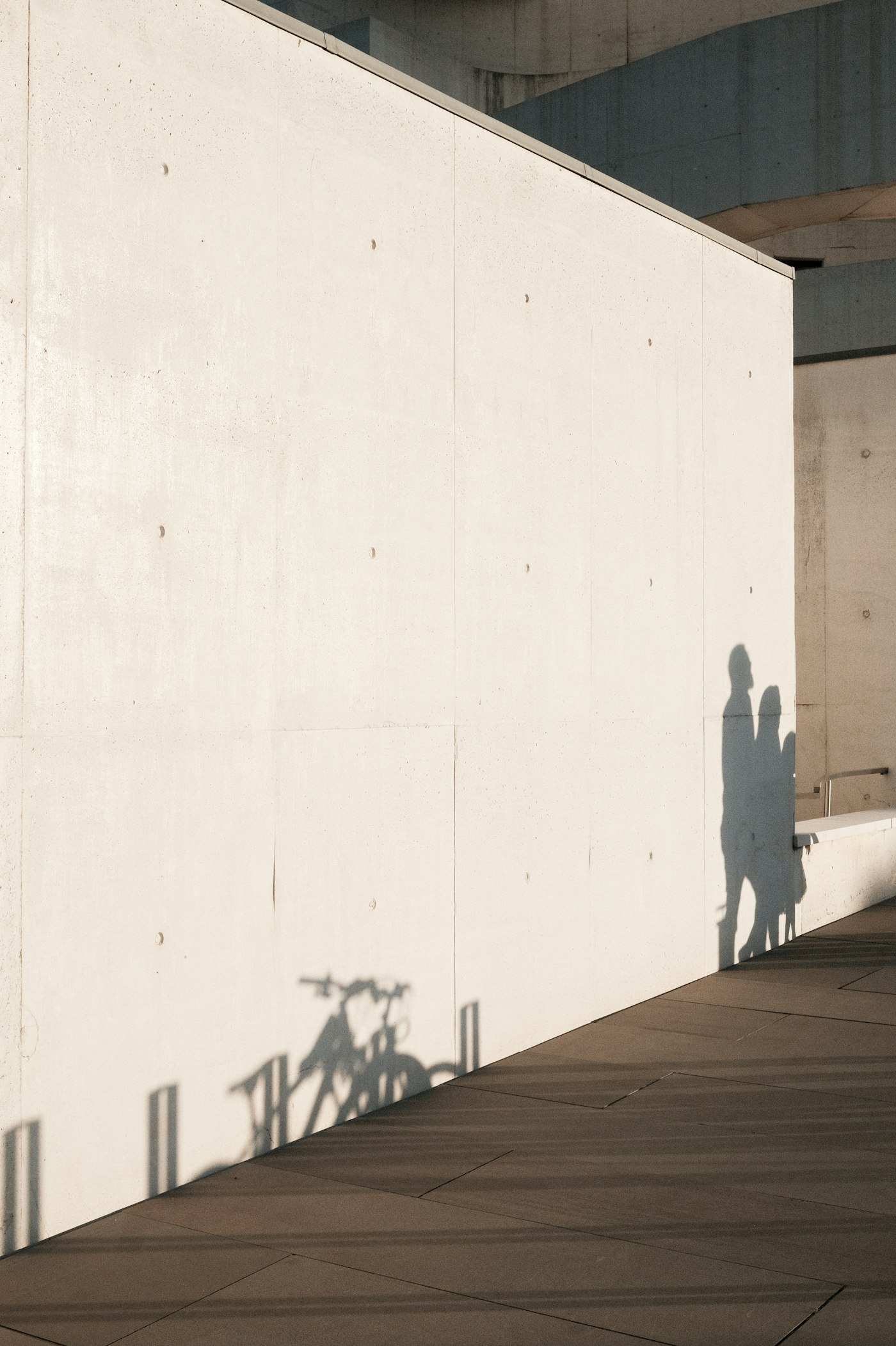 Shadows of people and a bicycle cast on a wall